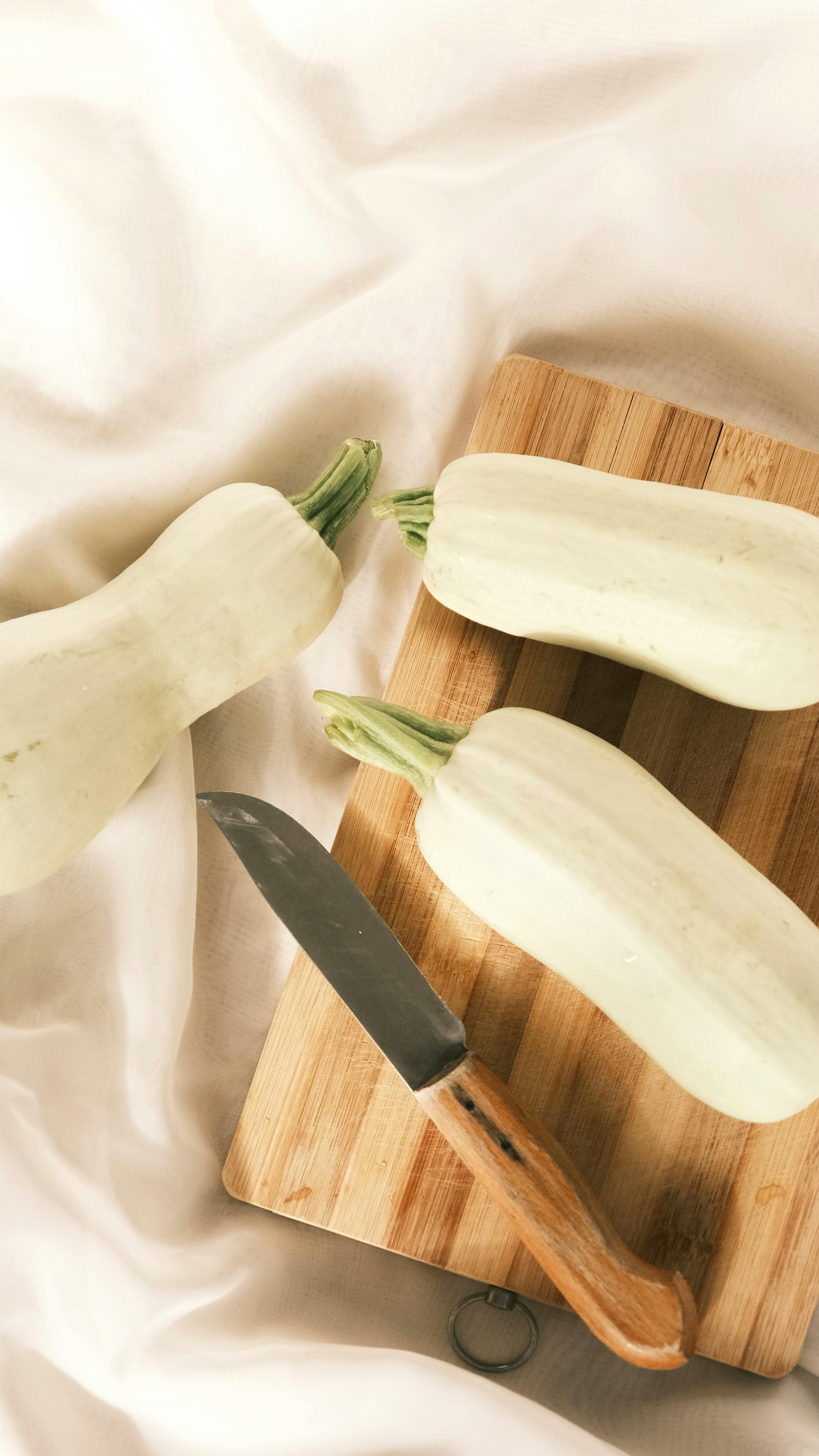 Une planche à découper sur laquelle sont posés des légumes et un couteau de cuisine.